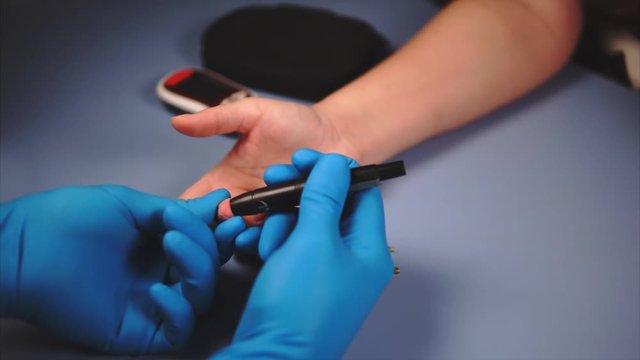 Close up testing for diabetes. Doctor using lancet and glucometer to measure female's patient blood sugar