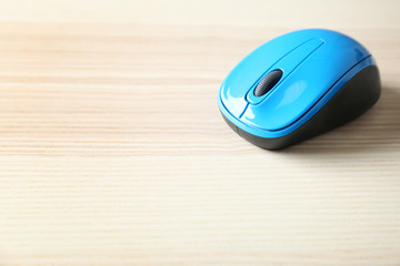Blue wireless mouse on light wooden table