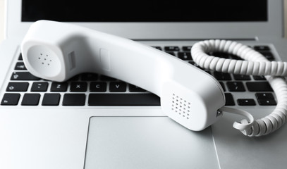 Modern laptop and telephone handset, close up