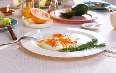 Plate with tasty fried eggs on wooden table