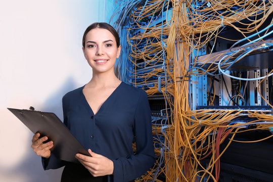 Beautiful young engineer with clipboard in server room