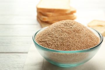 Small bowl of bread crumbs on wooden background
