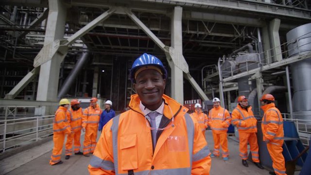  Portrait Smiling Manager At Industrial Plant With Team Of Workers Behind Him