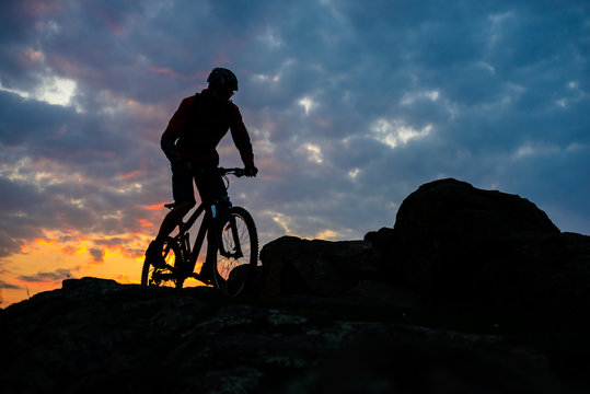 Silhouette of Cyclist Riding Mountain Bike on the Spring Rocky Trail at Beautiful Sunset. Extreme Sports and Adventure Concept.