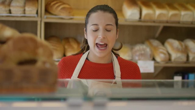  Friendly worker in bakery shop serving customer at the counter