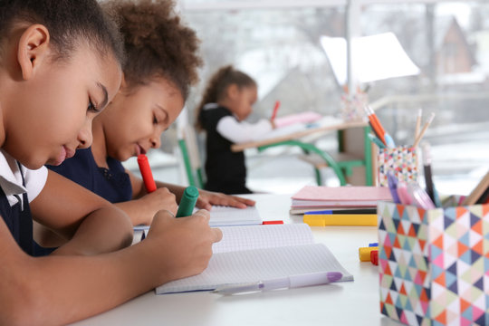 Cute African-American girls drawing at lesson