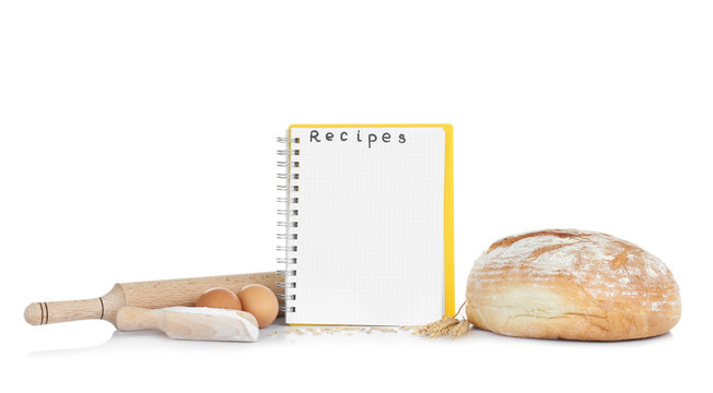 Open recipe book and bread on white background