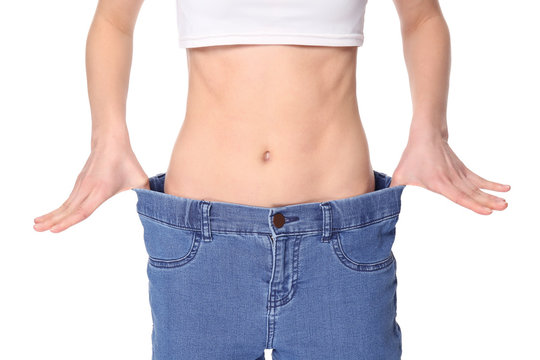 Diet concept. Young beautiful woman in large jeans on white background