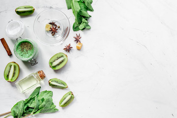 Skin care cosmetic with kiwi scrub on desk background top view mock-up