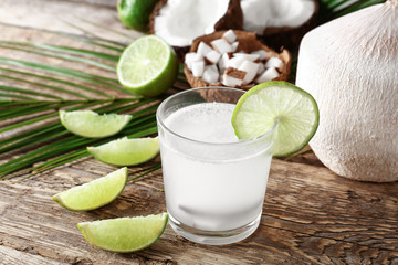 Glass of fresh coconut milk with lime on wooden table
