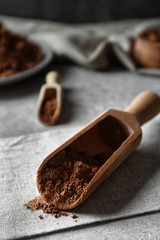 Wooden scoop with cocoa powder on napkin