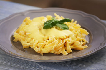 Plate with delicious pasta and cheese sauce on wooden table