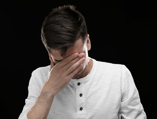 Fototapeta premium Handsome young man suffering from headache on black background