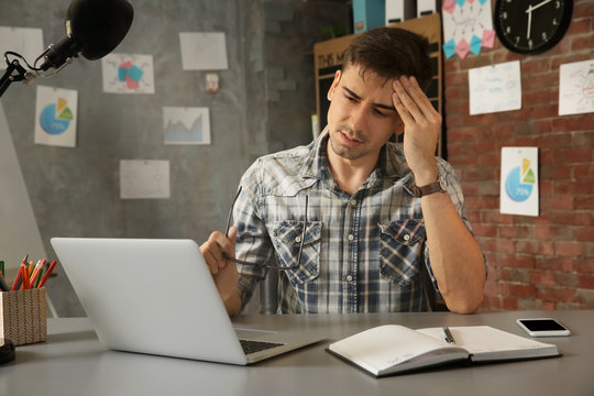 Handsome young man suffering from headache while working in office