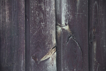 An old red door made of boards, covered with stains, chips, scratches