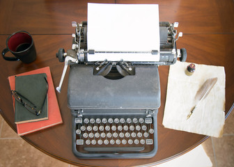 old black vintage typewriter sitting on wooden table next to old books, reading glasses, old letter with pen and quill. good for any author or writer with  creative dreams of journalism