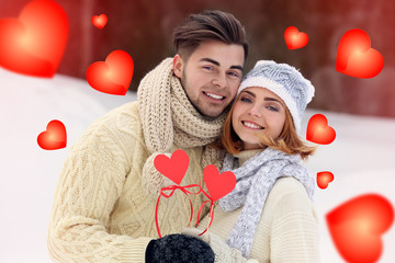 Young couple in love holding red paper hearts outdoors in winter © Africa Studio