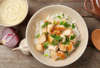 Delicious rice with chicken in bowl on table