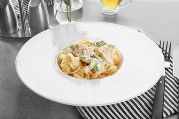 Plate of delicious pasta alfredo with chicken on table