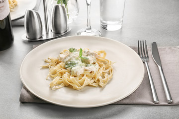 Plate of delicious pasta alfredo with chicken on served table