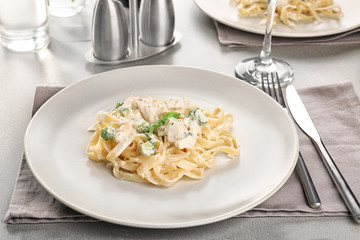 Plate of delicious pasta alfredo with chicken on served table