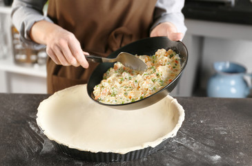 Woman making delicious chicken pot pie on kitchen table