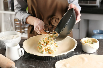 Woman making delicious chicken pot pie on kitchen table