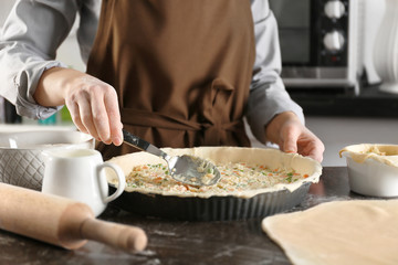 Obraz na płótnie Canvas Woman making delicious chicken pot pie on kitchen table