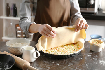 Woman making delicious chicken pot pie on kitchen table