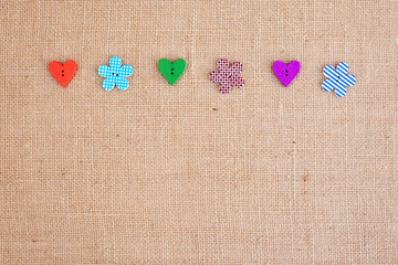 background - natural color burlap hessian with flower and heart shape buttons
