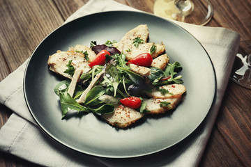 Delicious dinner with chicken, arugula, spinach and basil on black plate
