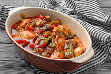 Delicious chicken cacciatore in baking dish on kitchen table