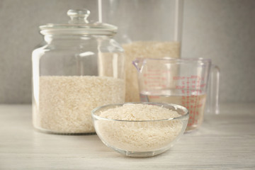 Kitchen ware with rice and water on wooden table