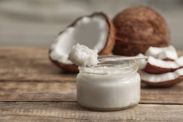 Fresh coconut oil in glass jar and spoon on wooden table
