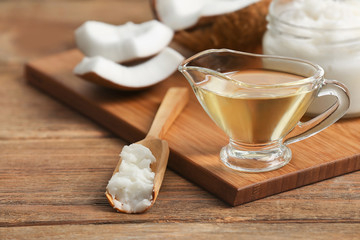 Fresh coconut oil in glassware and scoop on wooden table