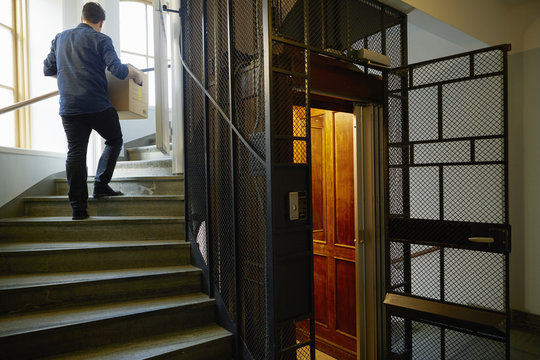 Sweden, Man walking on steps, carrying box