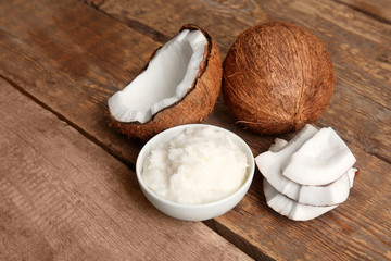 Bowl with fresh coconut oil and nut on wooden background