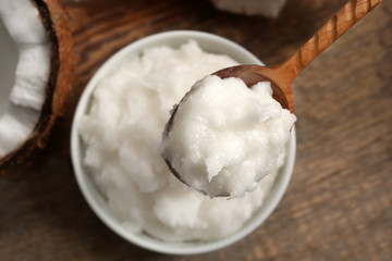 Wooden spoon with coconut oil over bowl on table © Africa Studio