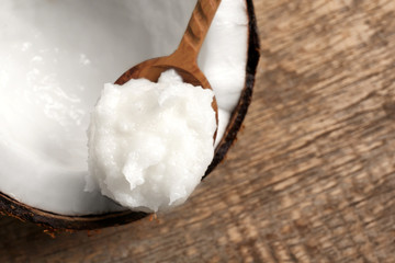 Wooden spoon with coconut oil on nut, closeup
