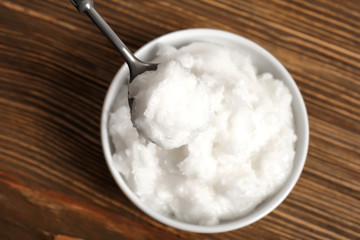 Spoon with coconut oil over bowl on table