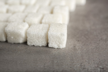 Fototapeta na wymiar Rows of sugar cubes on gray background