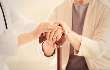Old and young women holding hands on walking stick, closeup