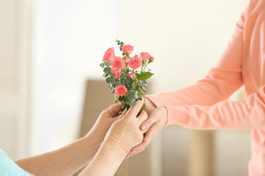 Female Hands Giving Flowers To Old Woman