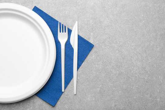 White plastic disposable tableware on gray background