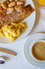 English breakfast on a plate with bread, orange juice and and coffee cup