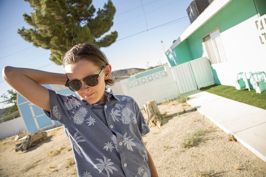 USA, California, Boy (14-15) wearing sunglasses standing outside of house