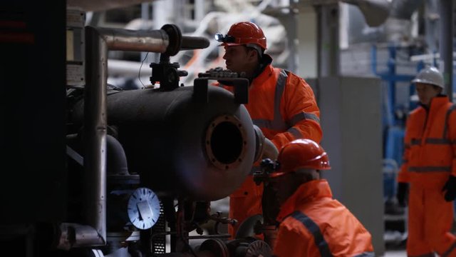 Engineering team carrying out maintenance in power plant with foreman watching