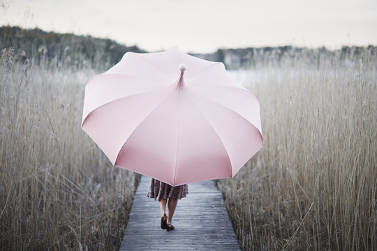 Sweden, Sodermanland, Woman with umbrella walking on wooden pier