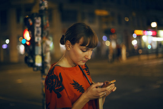 Germany, Berlin, Beautiful woman texting in city at night