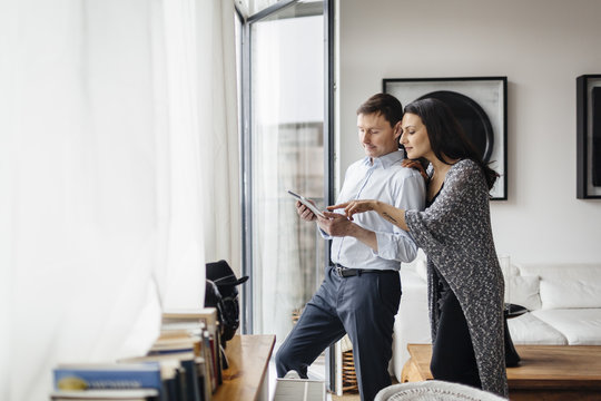Germany, Couple using tablet by window
